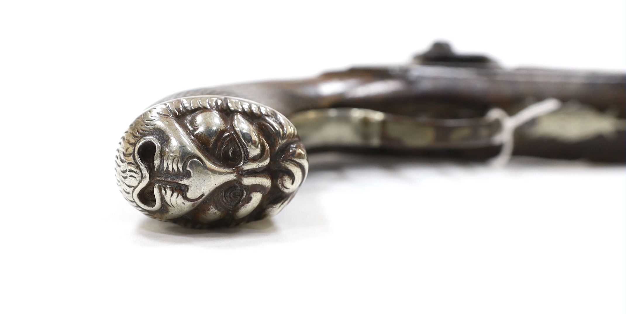 A 22 bore percussion holster pistol probably made for the Indian market, octagonal barrel with nickel sight, chequered walnut stock, engraved nickel furniture with grotesque mask butt cap